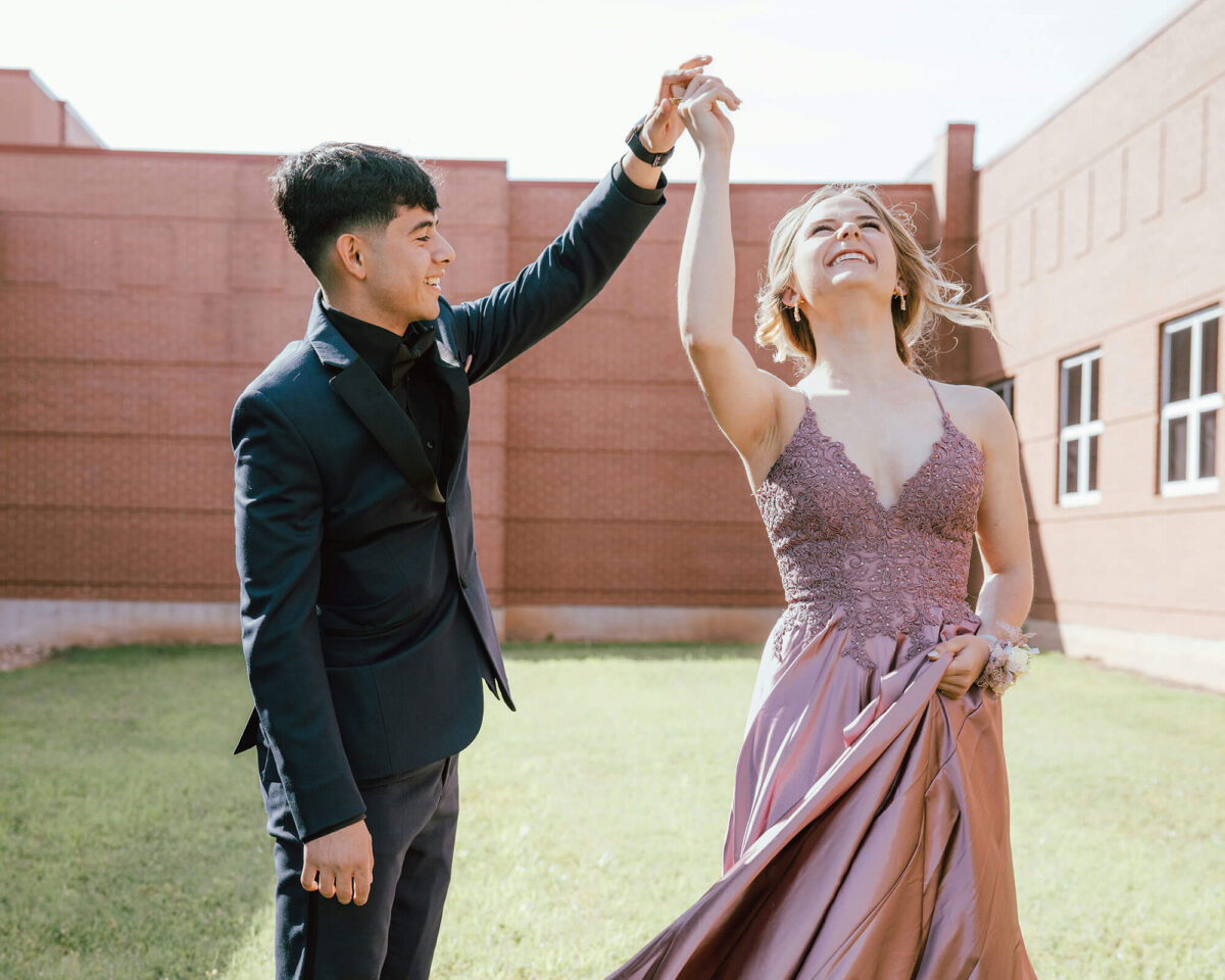 Teen couple in formal prom attire dancing outdoors
