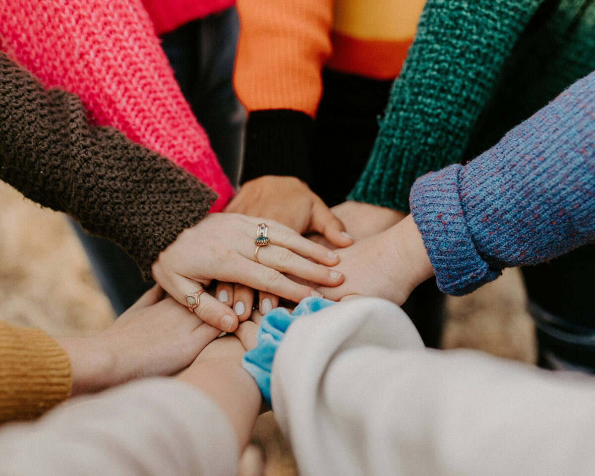 Diverse group of people placing their hands together in a circle, symbolizing community partnership