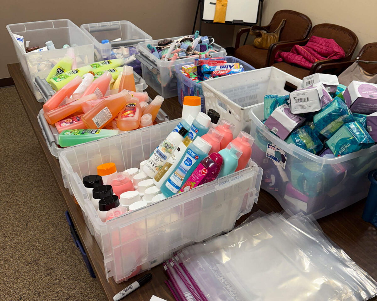 Plastic bins of toiletries and hygiene supplies sorted for assembly into receiving center backpacks