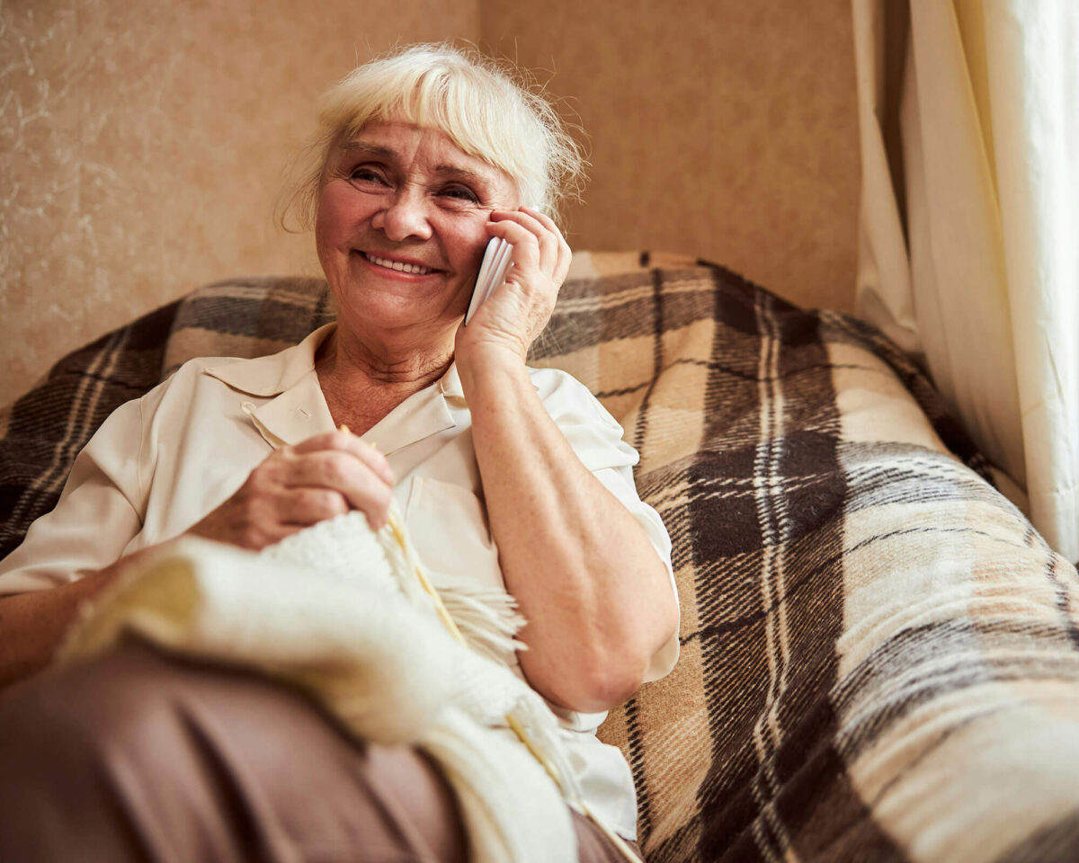 Senior woman smiling while talking on the phone from her armchair