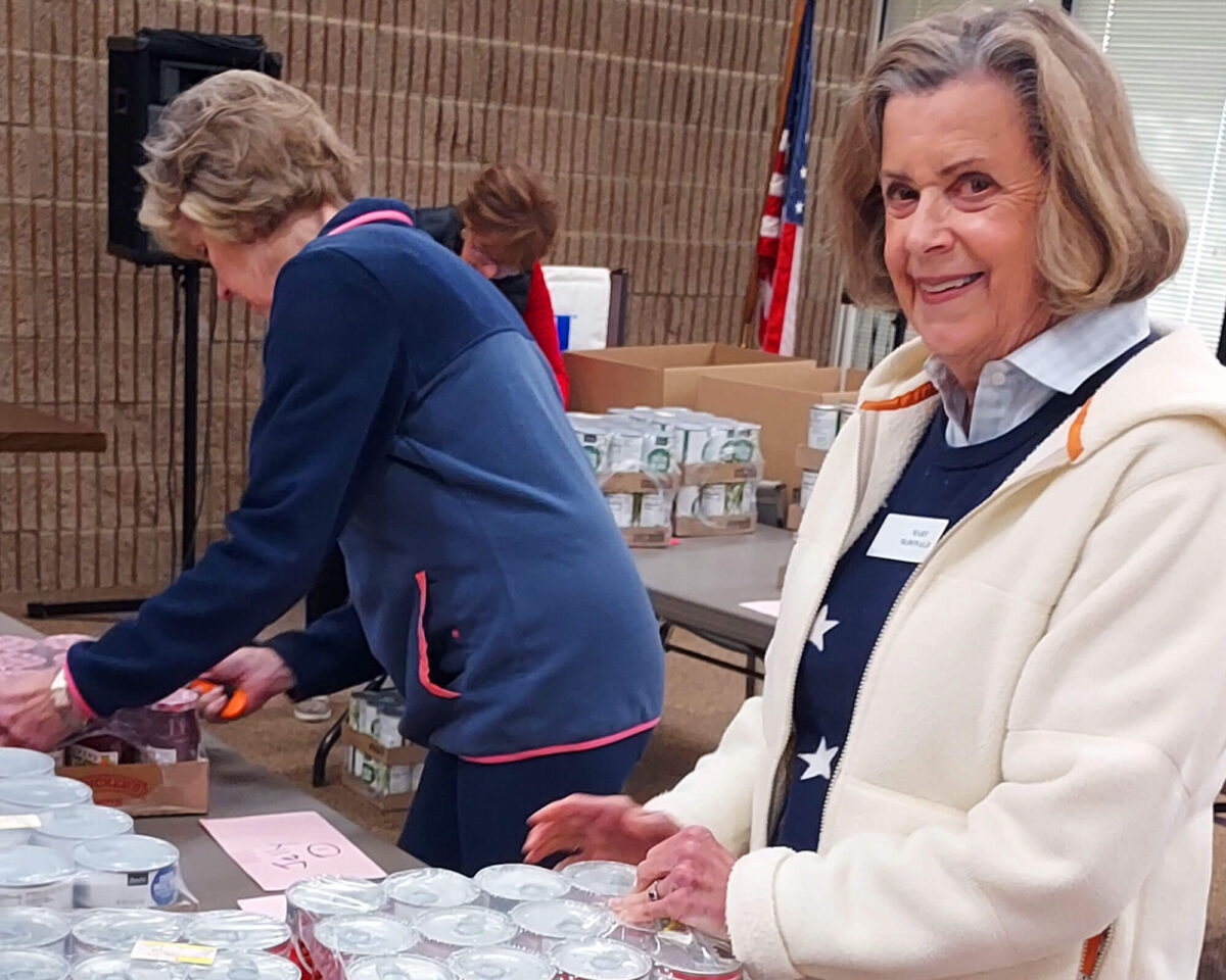 Two volunteers packing canned goods into cardboard donation food boxes