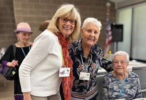 Three women smiling together at a community gathering