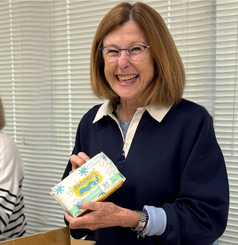 Volunteer laughing while sorting packages of baby wipes for community donations