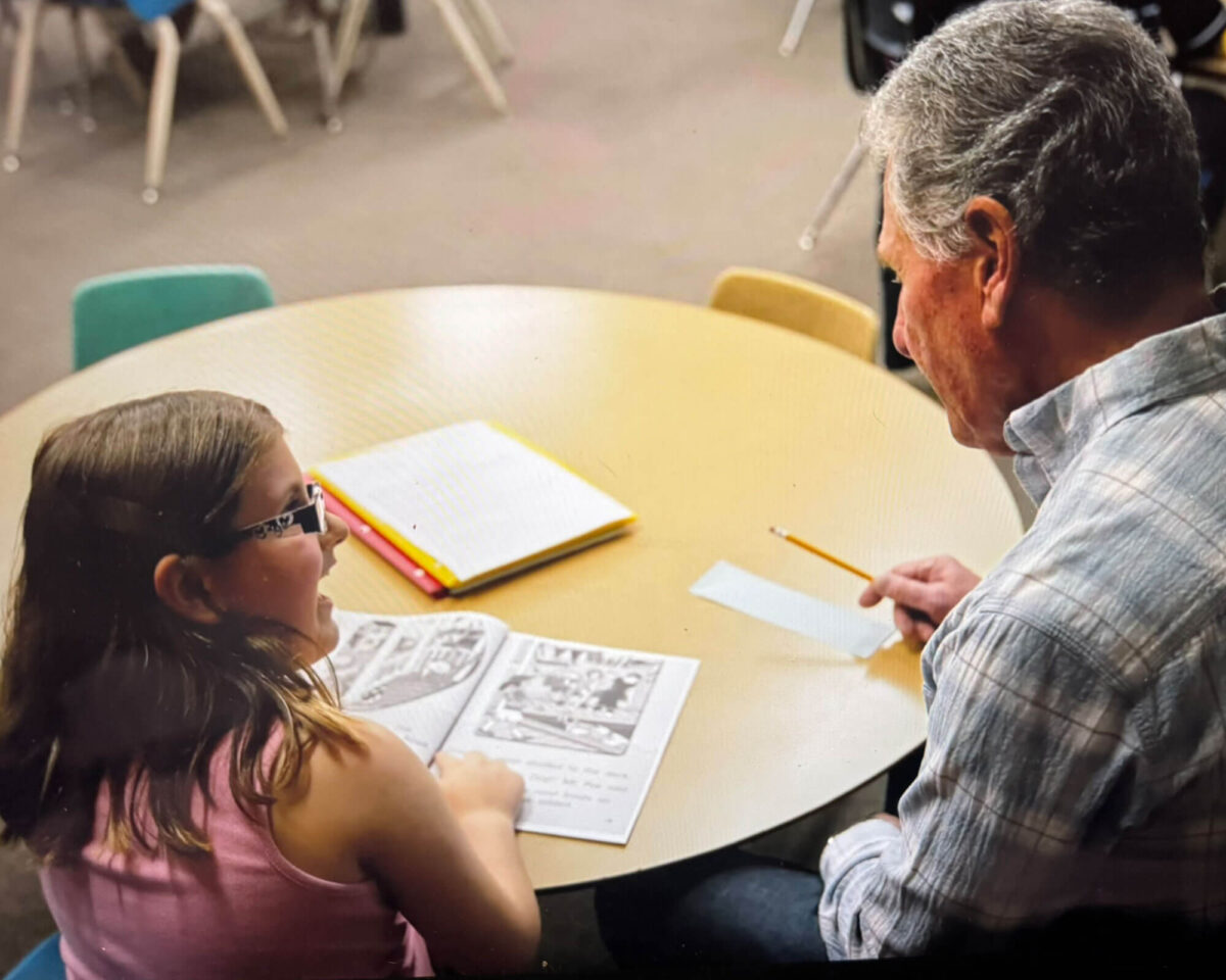 Adult volunteer listening as an elementary student reads aloud from a book during the LISTEN tutoring program
