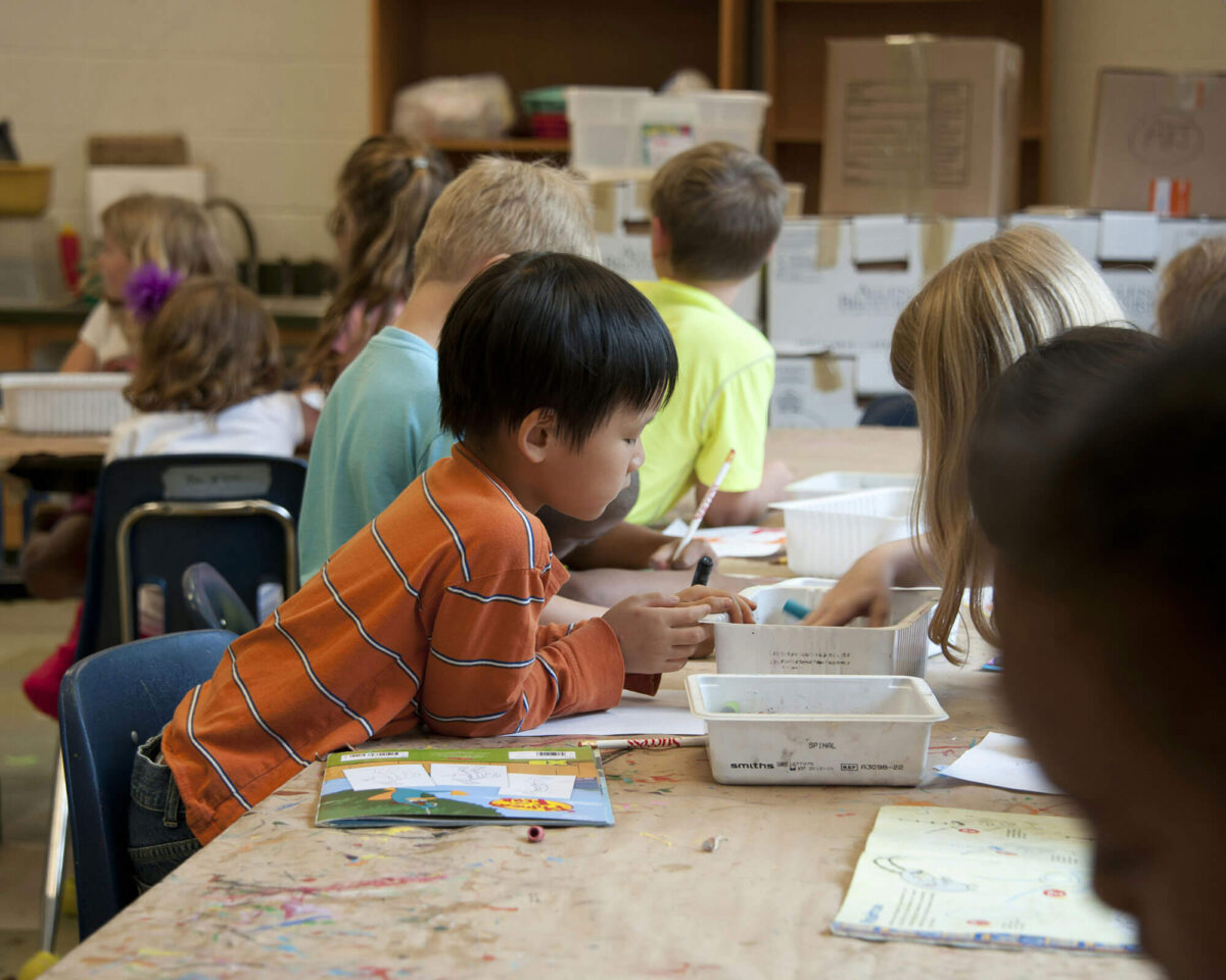 Elementary student concentrating on artwork at a classroom table during an Arts Discovery program session