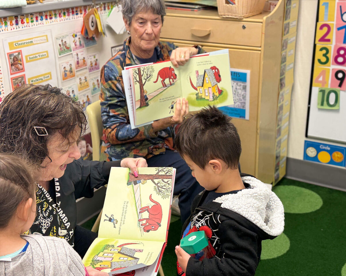 Volunteer reading a picture book aloud to preschool children during the READ program