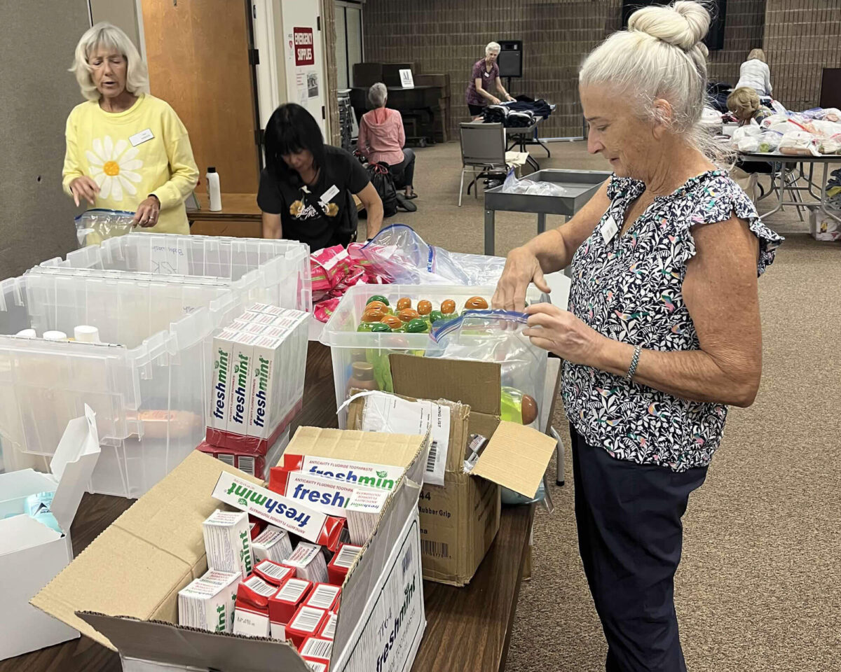 Volunteers organizing personal-care items in plastic bins to assemble On My Way kits