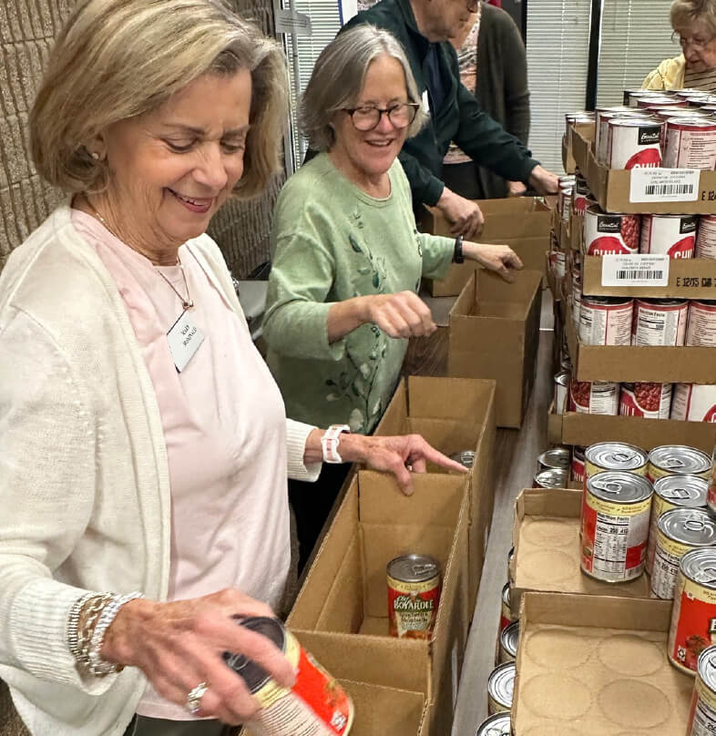 Two volunteers packing donated canned goods into food boxes