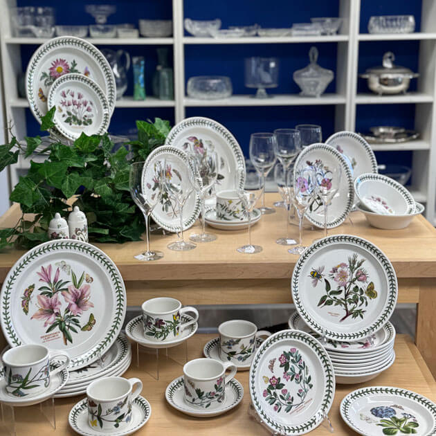Display of botanical-pattern china and crystal glassware available at the Giving Partners Thrift Shop